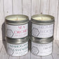 Stack of four silver candle tins with white labels.  In the scents of: Sea Orchid, Frosted Woods, Mahogany Lavender, and Marshmallow Fireside